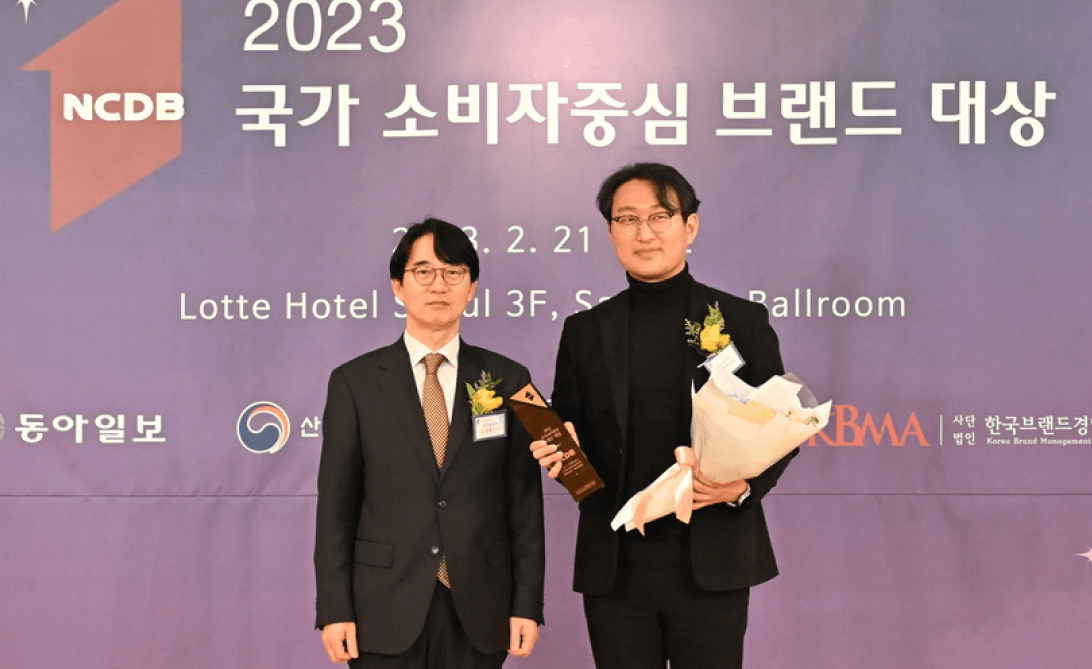 2023 NCDB 국가 소비자중심 브랜드 대상 수상식에서 두 남성이 트로피를 들고 있는 모습