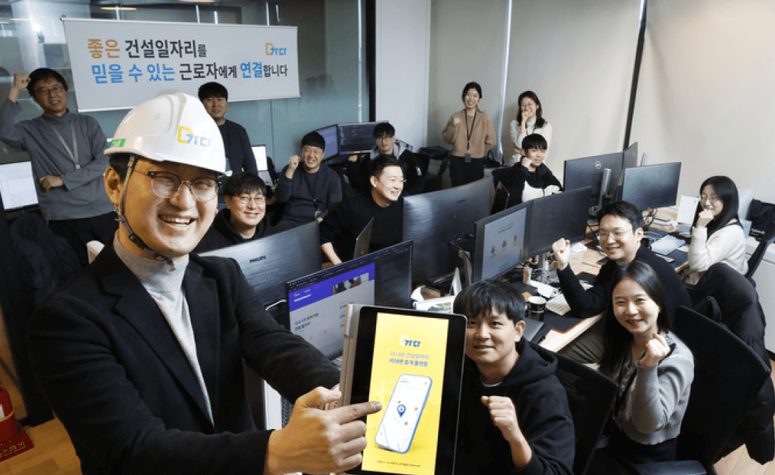 일용직 고용정보 모바일 앱 서비스 론칭을 축하하며 단체 사진을 찍는 개발팀 멤버들과 앱 아이콘